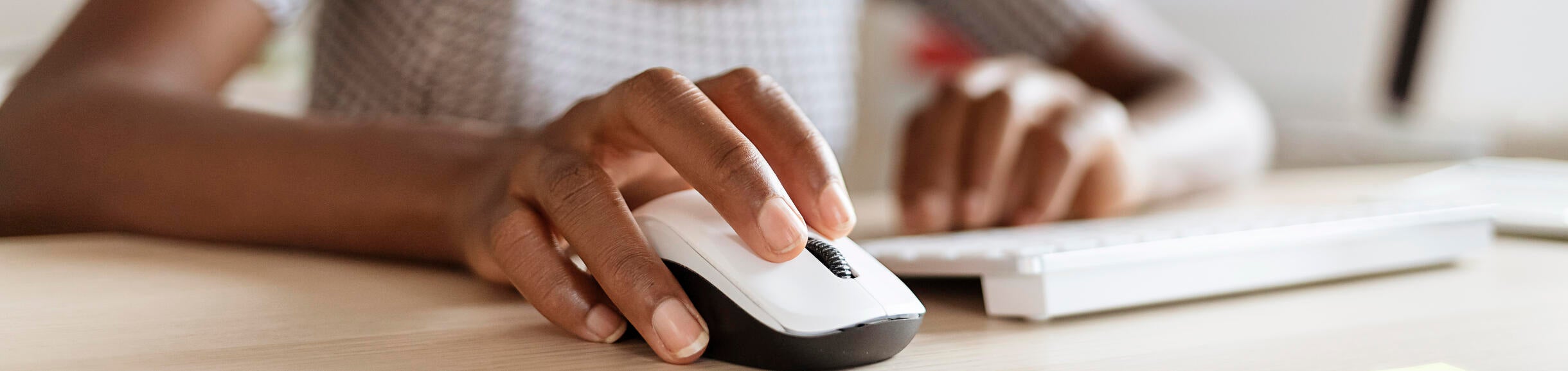 Person with their hand on a computer mouse. Two of their fingers rest on top of the mouse buttons.