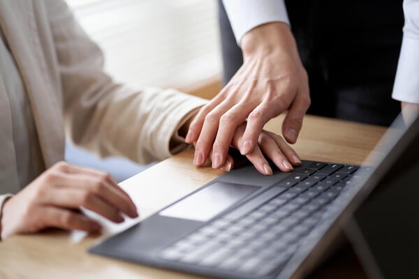 person touching the hand of another person who is using a laptop